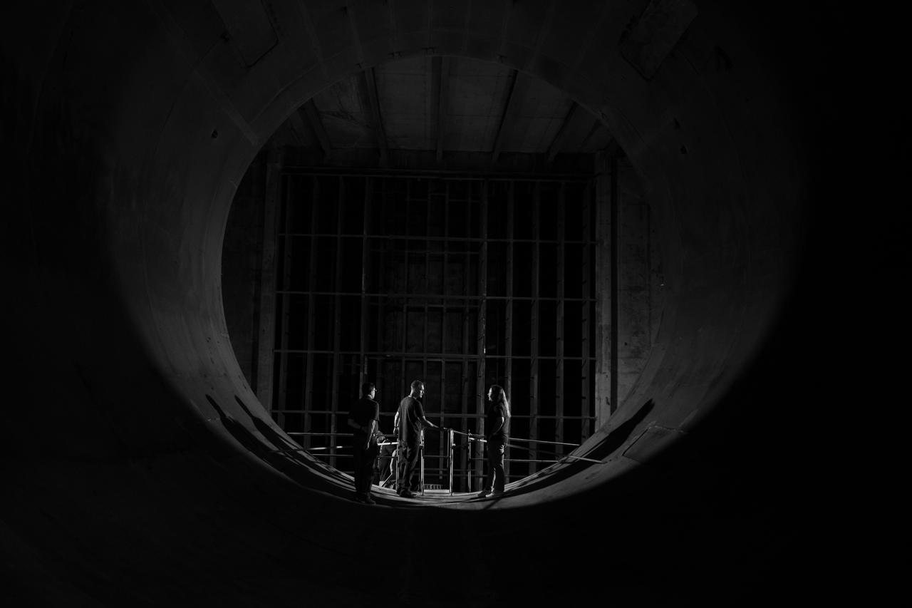 The interior of a large supersonic wind tunnel, with three engineers standing inside it for scale.