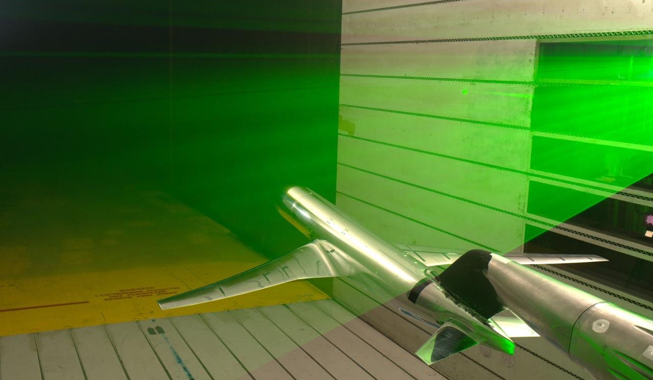 A laser sheet illuminating airflow over an aircraft model during a wind tunnel test.
